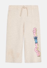 Beige shorts med dragsko i midjan, prydda med en färgglad grafik av Stitch och ordet "STITCH" i rosa och gult på sidan.