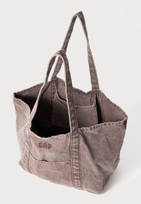 Graue Canvas-Tote-Tasche mit zwei Schulterriemen, offenem Oberteil und einer Außentasche mit gesticktem "GAP"-Logo auf der Vorderseite.