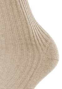 Beige ribbed sock featuring a textured knit pattern, with a smooth toe and reinforced heel for durability.