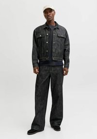 Dunkle Jeansjacke mit Knopfverschluss und Brusttasche, kombiniert mit passenden Hosen mit weitem Bein. Schwarzer, strukturierter Stoff, lässige Silhouette.