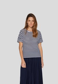 Striped cotton T-shirt in navy and white, short sleeves, round neckline, relaxed fit, paired with a long pleated navy skirt.