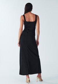 Črna maksi obleka z oprijetim korzetom, širokimi naramnicami in naborki v pasu, z zamaskiranim zadnjim zadrgo in gladkim materialom.