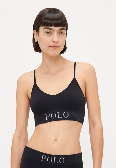 Zwarte draadloze bralette met een geribbelde textuur en een V-hals ontwerp. Heeft een bredere band met "POLO" geborduurd in het grijs. Verstelbare schouderbandjes.