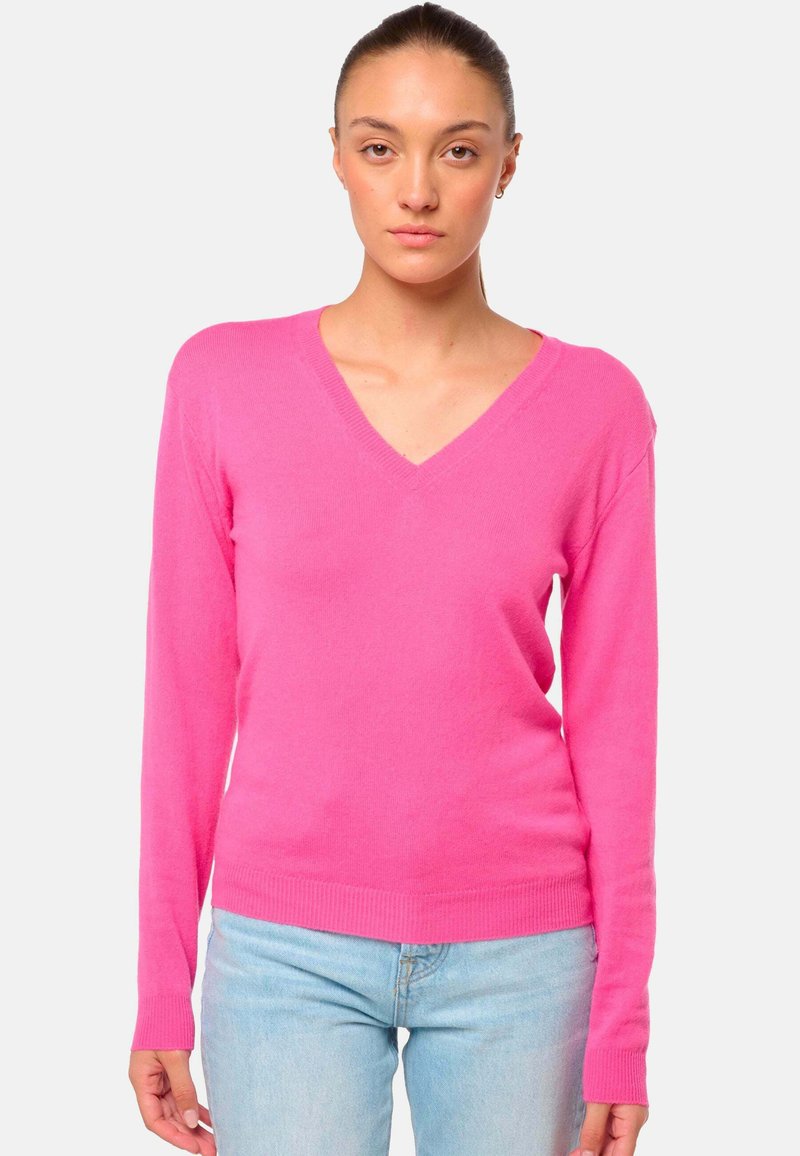 Rosa V-Ausschnitt-Pullover aus weichem Strickmaterial mit langen Ärmeln und Rippbündchen. Getragen mit hellblauen Jeans für den Kontrast.