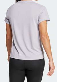T-shirt gris clair à manches courtes avec un col rond. Tissu doux et coupe légèrement ajustée. Porté avec des leggings noirs.