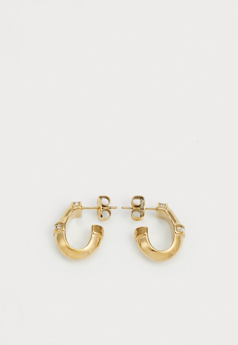 Pendientes de aro de oro en forma de C, con pequeñas piedras transparentes engastadas a intervalos. La textura suave y el acabado brillante realzan su diseño.