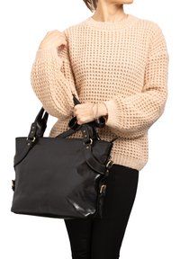 Sac fourre-tout en cuir noir avec quincaillerie dorée, doté de deux poignées et d'arêtes légèrement arrondies. Texture lisse et design structuré.