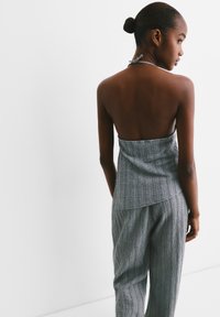 Sivi pleteni halter top s teksturiranim uzorkom i složenim dizajnom, uparen s odgovarajućim teksturiranim hlačama. Jednostavna i prilagođena silueta.