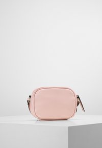 Borsa a tracolla finta pelle rosa con forma rettangolare, texture liscia e chiusura con zip. Presenta una tracolla corta.