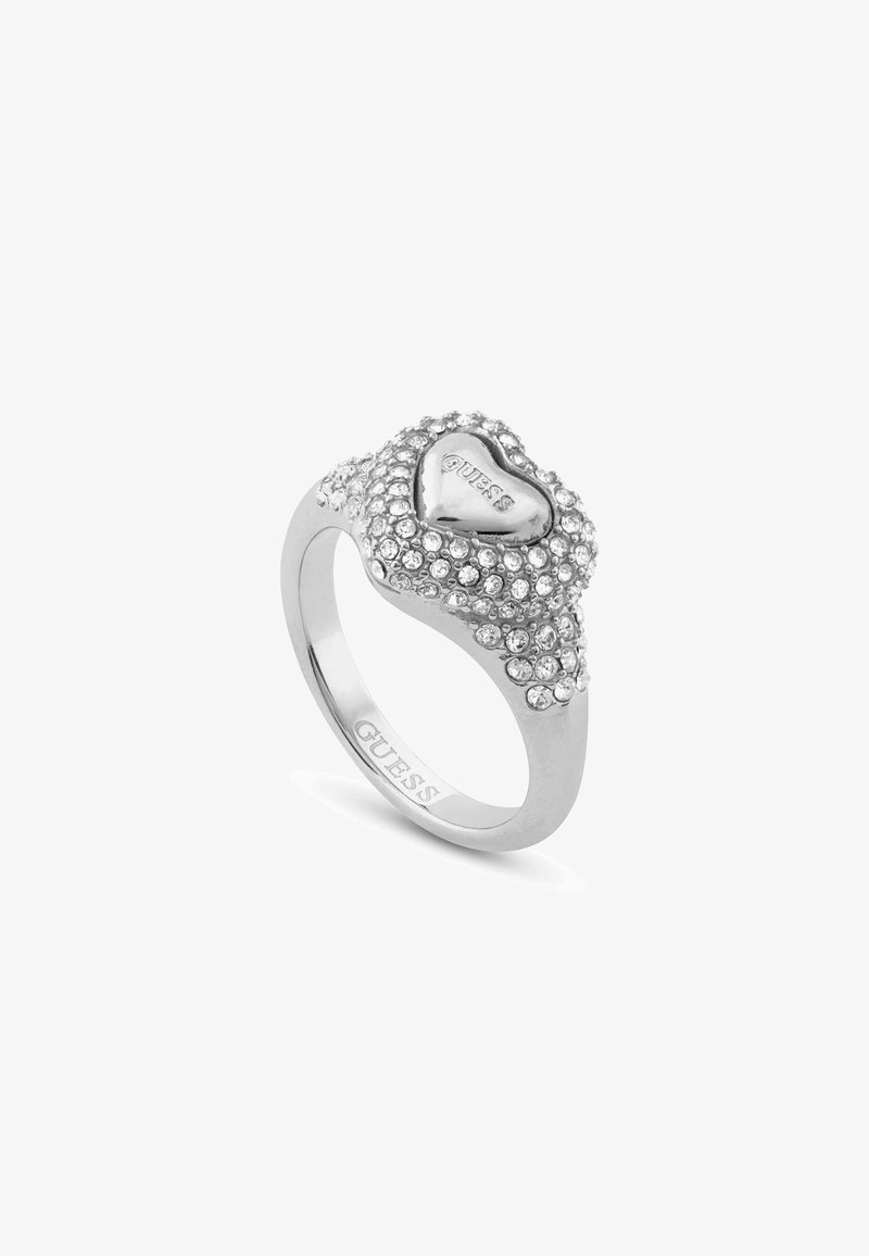 Anello a forma di cuore in argento con scintillanti strass, superficie texture e il logo "GUESS" inciso sulla banda.