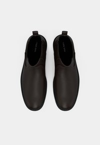 Brown leather slip-on shoes with a smooth texture and rounded toe, featuring side elastic panels and a sturdy black rubber sole.