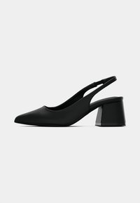 Talons aiguilles noires avec un bout pointu et une finition mate. Présente un talon bloc et un design découpé sur les côtés.