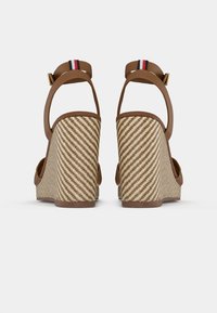 Sandales compensées marron avec un motif pied-de-poule, dotées d'une sangle et d'un fermoir doré. Design à dos ouvert avec des couleurs accentuées sur les sangles.