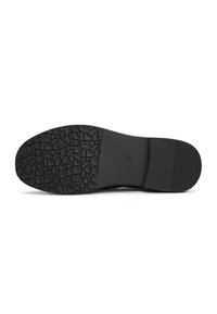 Suola di scarpa nera con superficie texture e a pattern, caratterizzata da una sezione liscia e un bordo rigato per presa e stabilità.