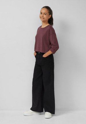 Geknipte, kastanjebruine, lange mouwen top gecombineerd met hoge taille, wijde zwarte broek en witte sneakers. Eenvoudig ontwerp, zachte textuur.