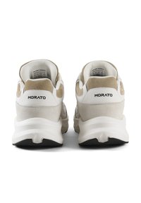 Baskets blanches et beiges avec une combinaison de cuir et de daim, col rembourré, semelle noire et marquage "MORATO" au niveau du talon.