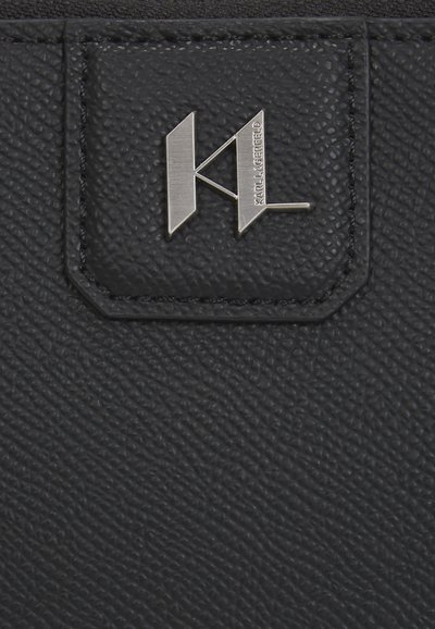 Черен текстуриран кожен портфейл с метален логотип в сребристо, включващ "K" и "L". С изтънчено шевно оцветяване и издаден логотип на странична вложка.