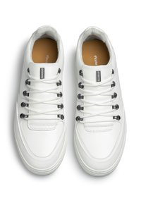 Sneakers bianchi in pelle con una texture liscia, dotati di accessori neri, lacci piatti, una linguetta imbottita e una soletta di colore crema.