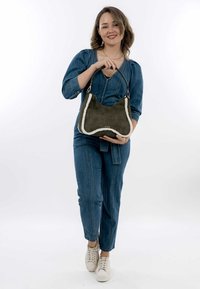 Olive green suede handbag with a cream faux fur trim, featuring a curved shape and a black shoulder strap. Logo detail visible.