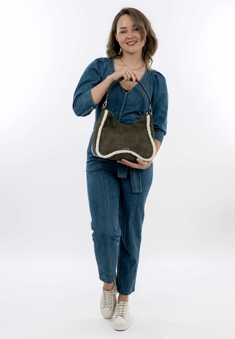 Olive green suede handbag with a cream faux fur trim, featuring a curved shape and a black shoulder strap. Logo detail visible.