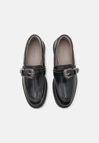 Sorte skinnloafers med en sølvspenne. Har sydd detaljer og rund tå. Teksturert såle for grep og holdbarhet.
