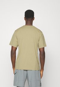 Olivgrön bomulls t-shirt med korta ärmar och rund halsringning, med en enfärgad design och avslappnad passform. Inga synliga logotyper eller mönster.