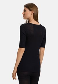 Top nero a maniche corte con scollatura rotonda, realizzato in tessuto a costine, caratterizzato da una silhouette aderente e una trama leggermente trasparente.