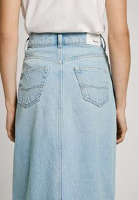Svetlo modra denim krila z srednje visokim pasom, ravno silhueto, dvema zadnjima žepoma in vidnim šivom, ki teče po sredini.