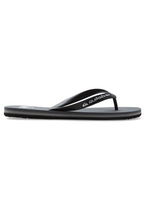 Tongs noires en caoutchouc, dotées d'une semelle intérieure texturée, de fines sangles et d'un détail logo sur la sangle. Semelle extérieure fine avec des stries.