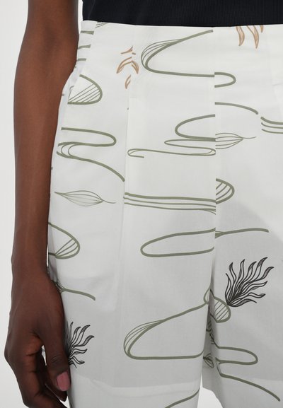 Λευκά παντελόνια με πράσινα και καφέ αφηρημένα σχέδια γραμμών; λείος ύφασμα; διαθέτουν πτυχές και πλαϊνές τσέπες για επιπλέον λεπτομέρεια.