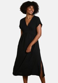 Black midi dress with short sleeves, V-neckline, and empire waist. Features side slits for ease of movement, made from soft fabric.