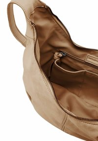 Beiges Leder-Tascheninnere mit einer glatten Textur, das eine Reißverschlusstasche und ein Hauptfach aufweist, detailliert mit einem dunkelbraunen Reißverschluss.