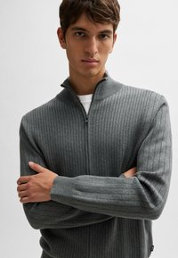 Gray ribbed sweater with a high collar and half-zip closure. Features long sleeves and textured fabric. Reinforced cuffs and hem.