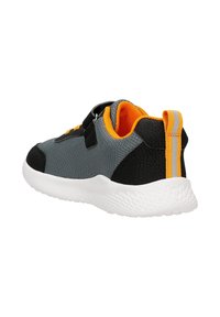 Dziecięcy szary i czarny trampek z pomarańczowym wnętrzem, z rzepem i białą teksturowaną podeszwą, przedstawiony z tyłu i pod kątem bocznym.