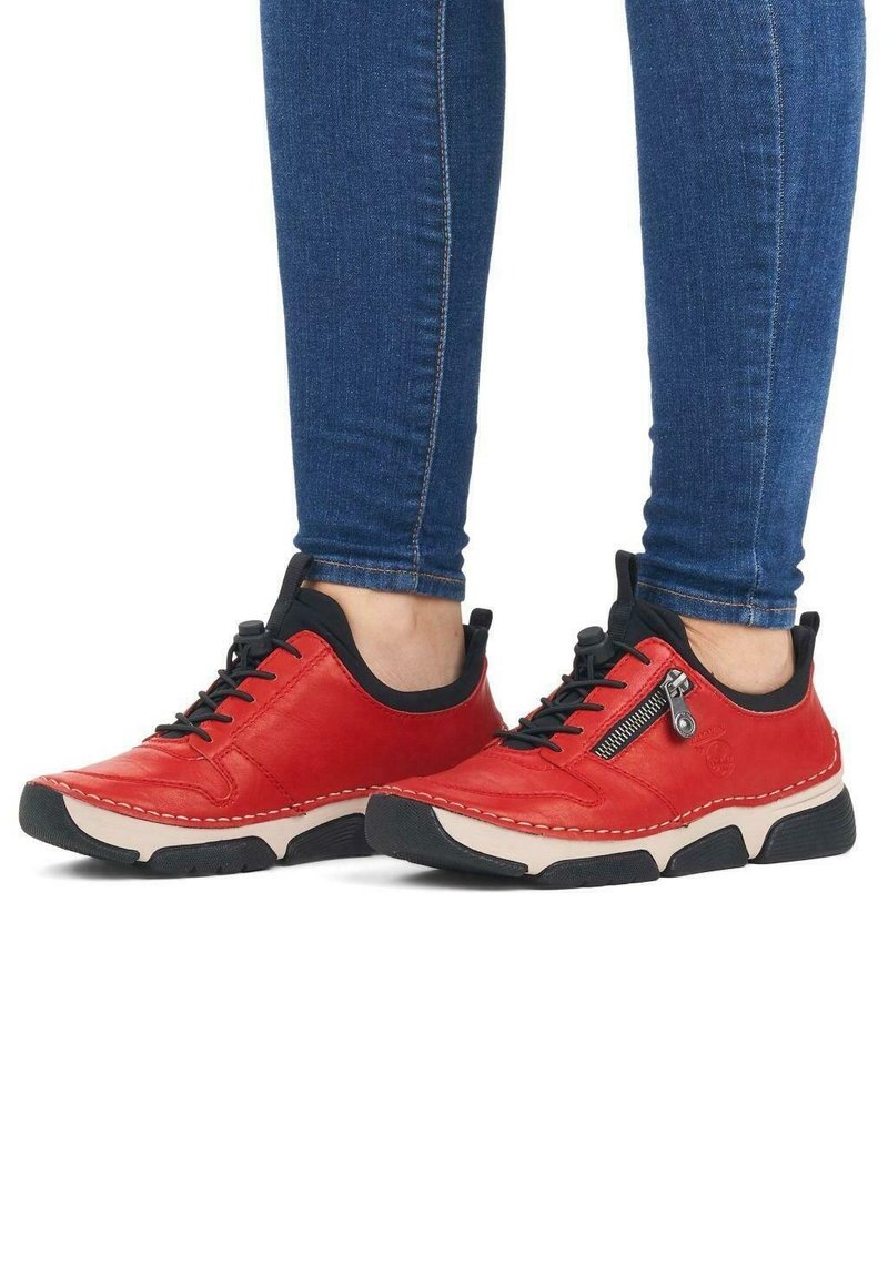 Red leather sneakers with black accents, laces, and a side zipper. Features rubber sole with white stitching for added contrast.