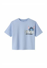 Vaaleansininen puuvillapaita, lyhyt hiha, jossa on kuvio hahmosta, jolla on suuret korvat ja teksti "Stitch Out of This World."