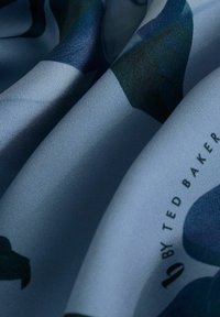 Foulard di seta nelle tonalità di blu con motivi floreali astratti in verde scuro. Texture liscia con il marchio in un angolo.