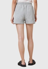 Shorts en coton gris avec une taille élastique, de longueur mi-cuisse, et texture lisse, associés à des sandales noires à enfiler.