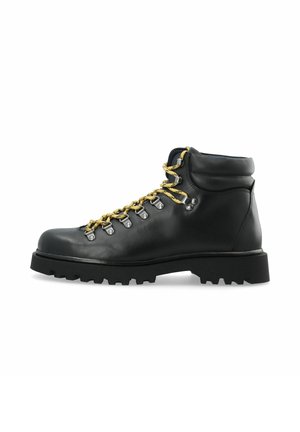 Botte de randonnée en cuir noir avec lacets jaunes, œillets métalliques, col rembourré et semelle épaisse à crampons, vue de profil sur fond blanc.