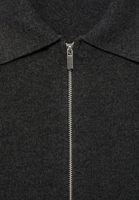 Black zip-up sweater with a soft, textured fabric. Features a collar and a metallic zipper running down the front. Minimalist design.