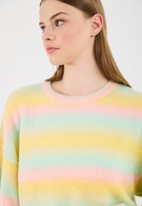 Pulover cu dungi pastelate, având o textură moale în nuanțe de galben, roz și mentă. Guler clasic, rotund, cu margine răsucită.