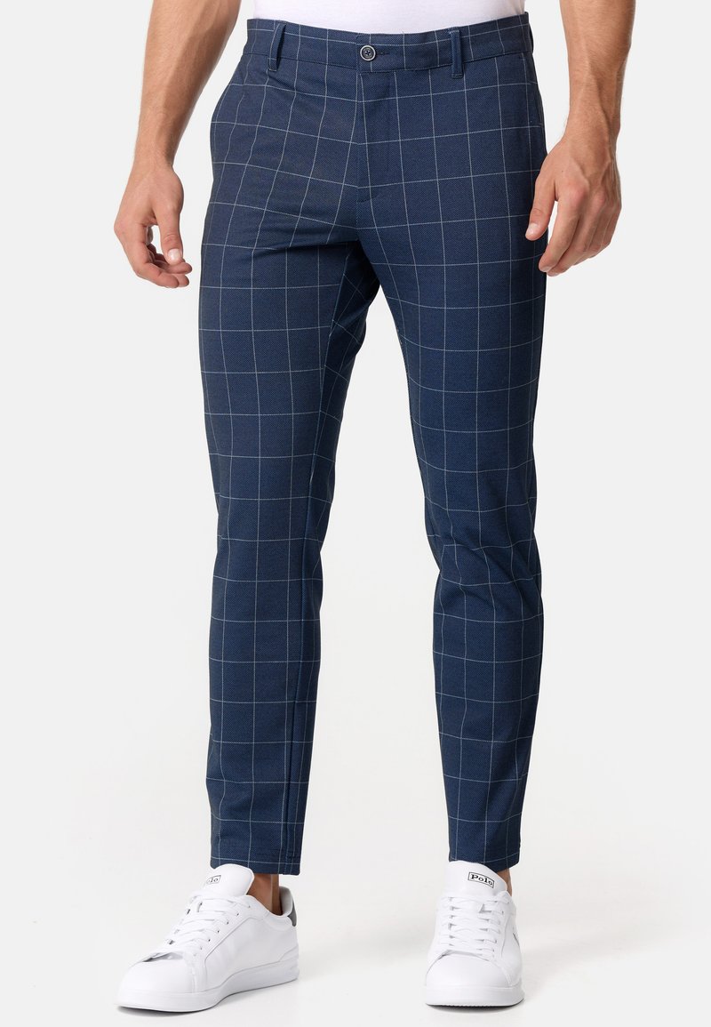 Mørkeblå ternede bukser lavet af vævet stof med slim fit. Har et hvidt rutenetmønster og en flad front med knaplukning.