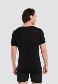 Black short-sleeve shirt with a relaxed neckline, made of lightweight fabric. Features smooth texture and fitted design.