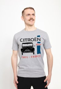 Šedé bavlněné tričko s grafikou vintage vozu Citroën 2CV a textem "CITROËN PARIS FRANCE" v černé a červené barvě. Krátké rukávy, volný střih.
