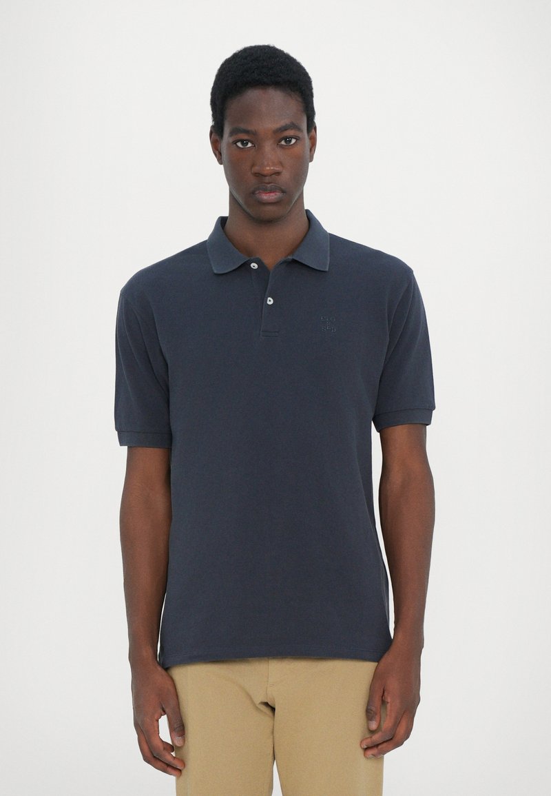 Ναυτικό πόλο μπλούζα από βαμβάκι, με κλασικό γιακά, κοντά μανίκια και διακριτό λογότυπο στο στήθος. Λείο ύφασμα. Χαλαρή εφαρμογή.