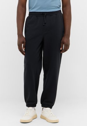 Schwarze Jogginghose aus weichem Stoff, mit elastischem Bund und Kordelzug, mit Bündchen an den Knöcheln und seitlichen Taschen.