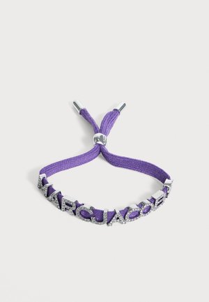 Bracelet en tissu violet avec des lettres argentées formant le mot "MARC JACOBS", ornées de cristaux clairs et d'ajusteurs en métal argenté.