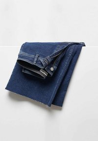 Blauwe spijkerbroek gevouwen op een witte ondergrond, met zichtbare tailleband, rits, knoop en rafelige randen van de stof.