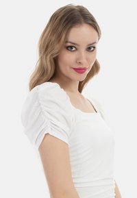 Fehér felső, rövid, összegyűrt puffujjú és négyzet alakú kivágással. Sima textúrájú, formás kialakítás, amely kiemeli a sziluettet.