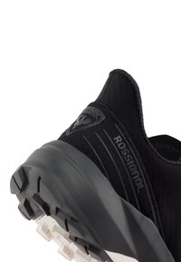 Scarpa sportiva nera con tomaia testurizzata, caratterizzata da un logo di marca, suola imbottita e suola esterna con trazione robusta.